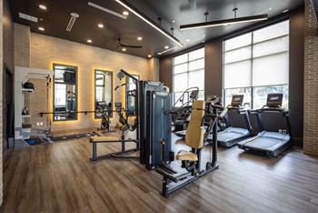A gym with a lot of exercise equipment and windows